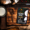 Siam Premium Coconut Milk package on a wooden cutting board with coconut and ingredients in the background.