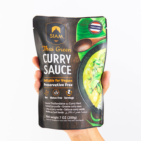Packaged Thai Green Curry Sauce with Siam branding held by a hand on a white background