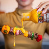 SIAM Peanut coconut sauce being poured onto a skewer with vegetables and meat.
