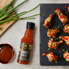 Siam Sweet Chilli sauce bottle with wings and sauce on a slate board