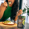 Person eating a meal with a package of Thai Green Curry Sauce in the foreground