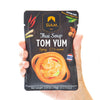 Hand holding a Siam Thai Soup Tom Yum package against a white background